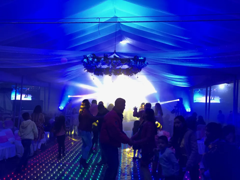 Interior de una carpa con telas iluminadas en azul y una pista de baile.