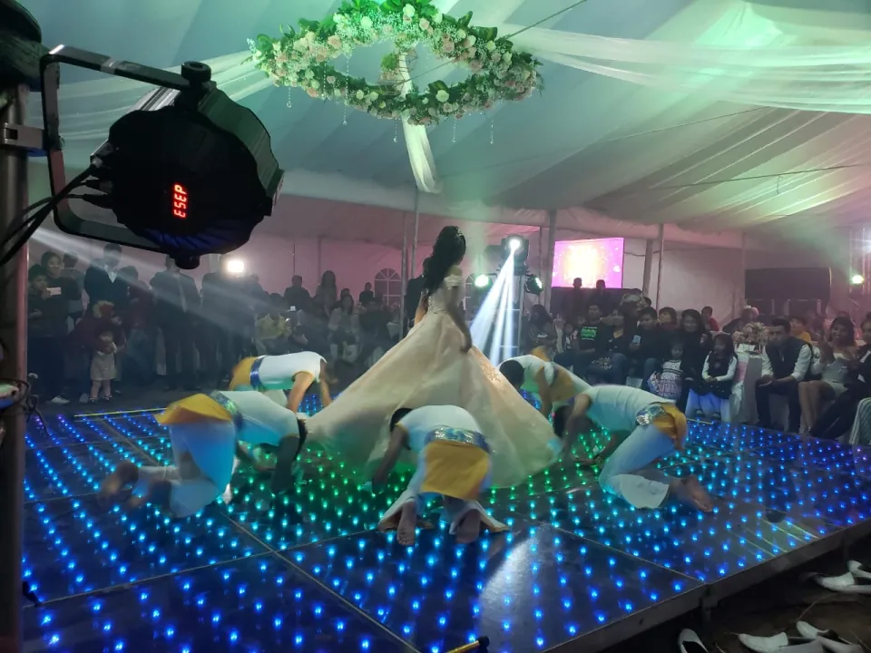 Pareja bailando sobre una pista LED azul frente a los invitados.