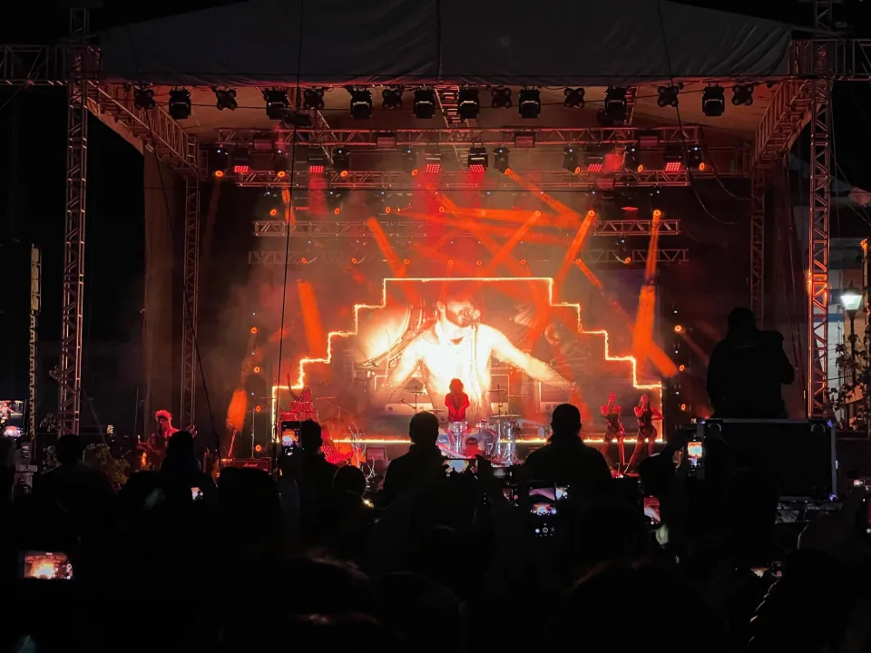 Escenario con pantalla LED e iluminación roja, visto desde el público.